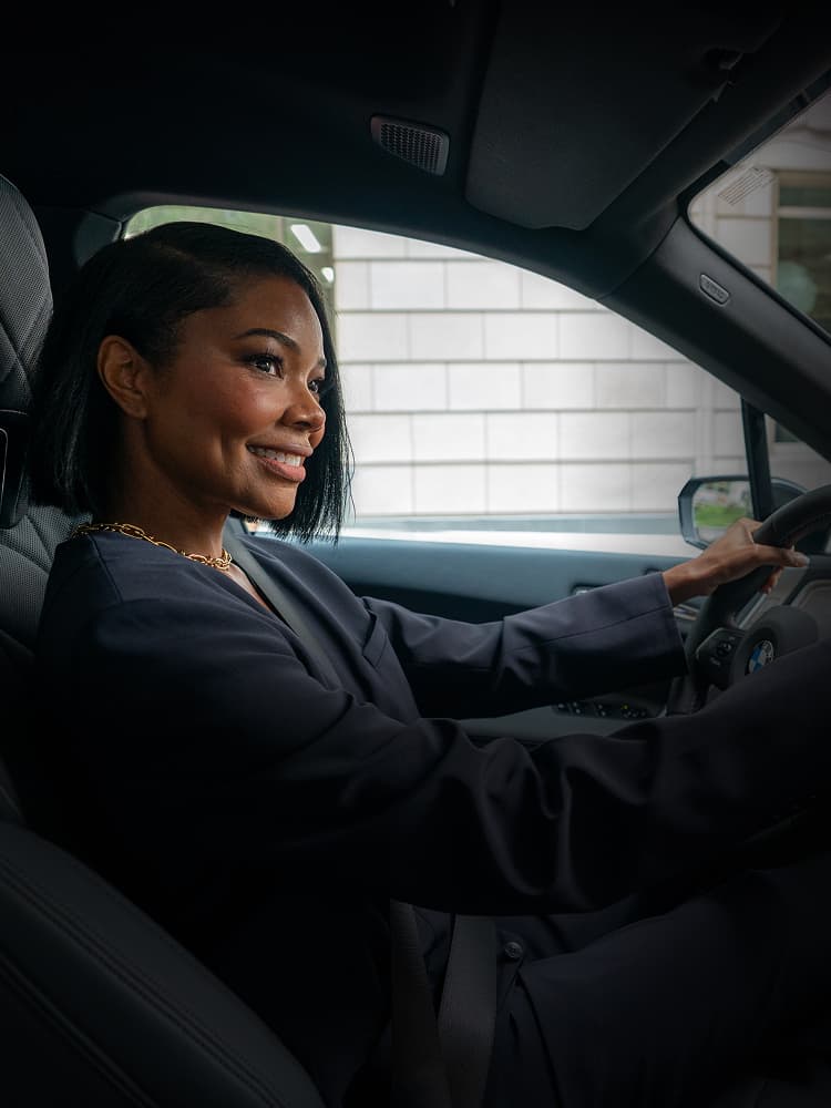A shot from the passenger's seat of Gabrielle Union smiling while driving the BMW iX